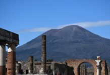 Famous Volcanoes in Italy: Fiery Trio Mt Vesuvius rises up above the ruins of the Firum in Pompeii.