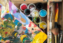 Paints of different colors and dirty brushes on an easel.