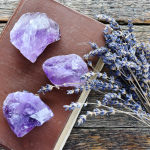 Amethyst stones on a leather-bound book with lavender, representing religious gemstones