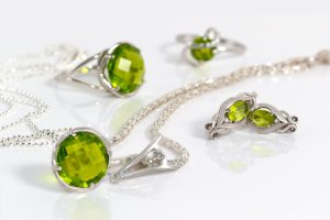 silver earrings and pendant with peridot on background chain and rings on white