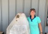 rockhounding woman standing next to giant crystal as tall as her