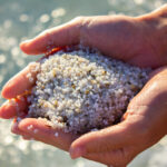minerals in beach sand include quartz in sand being held in hands on the beach