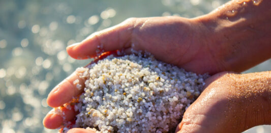 Rock Science: Minerals in Beach Sand minerals in beach sand include quartz in sand being held in hands on the beach