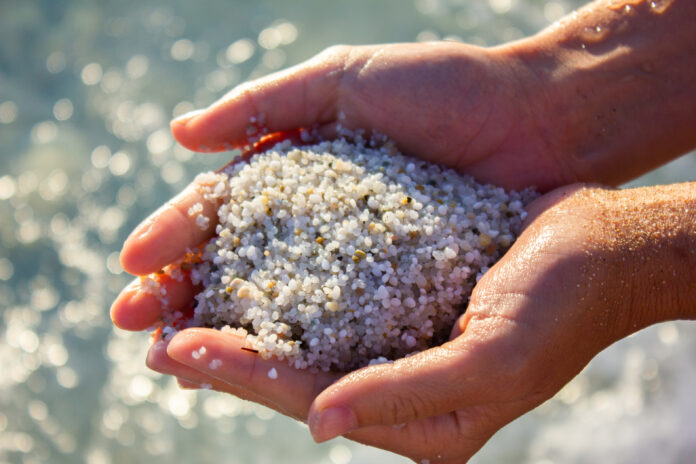 minerals in beach sand include quartz in sand being held in hands on the beach
