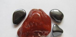 a large red hematite stone surrounded by gray magnetic hematite stones