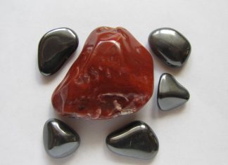 a large red hematite stone surrounded by gray magnetic hematite stones
