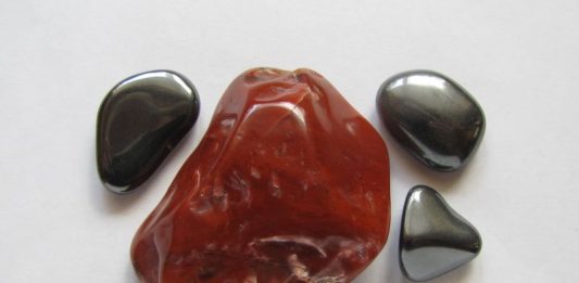 a large red hematite stone surrounded by gray magnetic hematite stones