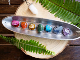 seven chakra stones over wooden background, energy healing concept