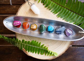 seven chakra stones over wooden background, energy healing concept