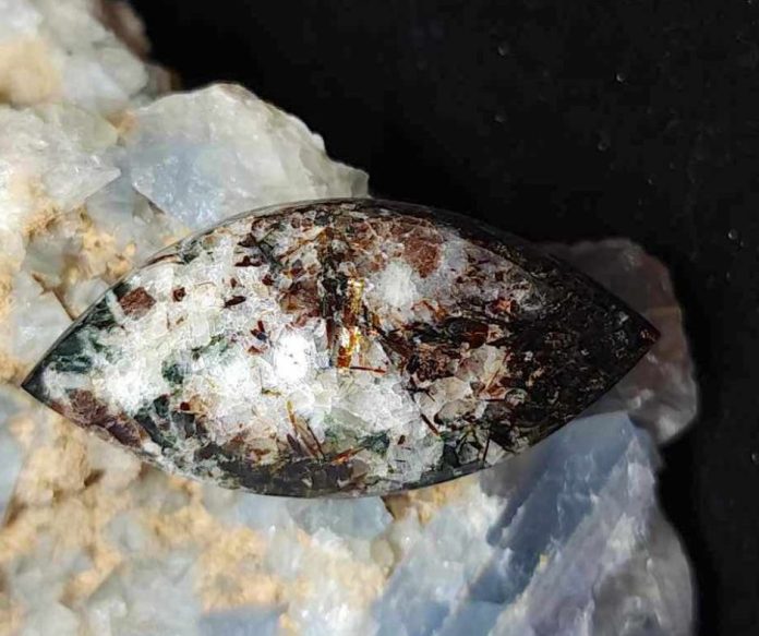 astrophyllite-1 astrophyllite cabochon with mineral background