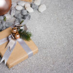 A a rock collecting gift box wrapped by brown paper with christmas theme decoration on stone floor.