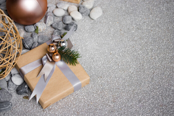A present box wrapped by brown paper with christmas theme decoration on stone floor and texture A a rock collecting gift box wrapped by brown paper with christmas theme decoration on stone floor.