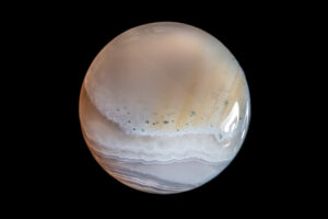 Single moonstone with white and brown wave-like patterns on a black background