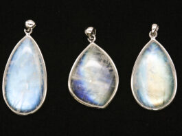 Moonstone Field Guide: Facts & Uses Three moonstone pendants with blue adularescence displayed on a black background
