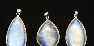 Moonstone Field Guide: Facts & Uses Three moonstone pendants with blue adularescence displayed on a black background