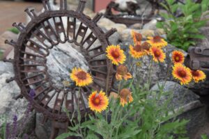 rock, metal sculpture and blanket flowers used in landscaping with stone