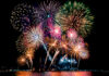 Beautiful colorful fireworks display showing on the sea beach with multi color of reflection on water.