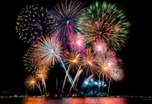 Beautiful colorful fireworks display showing on the sea beach with multi color of reflection on water.