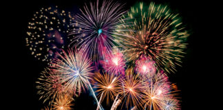 Beautiful colorful fireworks display showing on the sea beach with multi color of reflection on water.