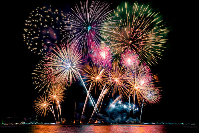 Amazing beautiful colorful fireworks display on celebration nigh Beautiful colorful fireworks display showing on the sea beach with multi color of reflection on water.