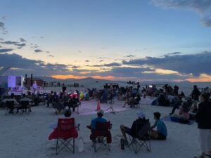 Visitors to White Sands National Park gather on lawn chairs for a sunset ranger program.