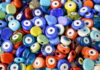 Evil Eye Beads: History, Meaning and Origins A scoopable pile of evil eye beads of all different colors