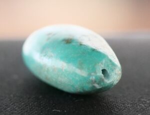 Turquoise bead with rough gemstone fractures and dull luster.